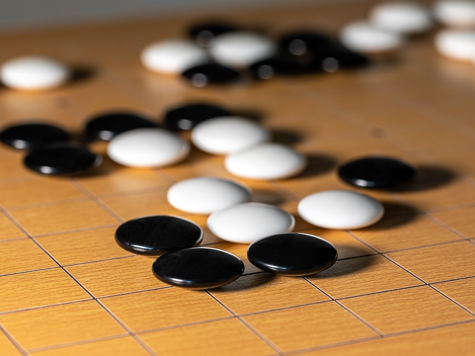 Close-up of black and white stones on a Go board mid-game. AlphaGo learned the same objective twice: first by supervised learning on expert games, then by self-play reinforcement learning.
